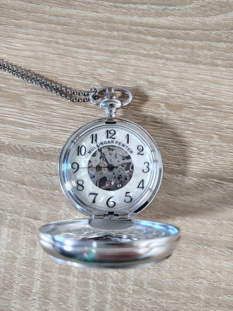 a silver pocket watch with gears showing on the face